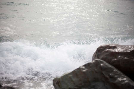 Sea surf beats on stones. Large boulders on the seashore. Troubled sea. Cloudy weather on the shore.の写真素材
