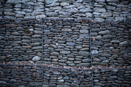 Stones in a metal mesh. Pebble texture. Building block assembled from natural materials. Powerful...