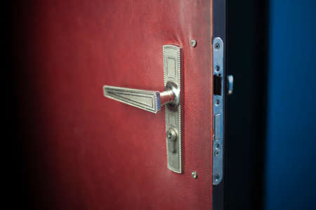 Open door to the apartment. Door handle and lock. Broken metal door. Close-up shot of details of the entrance to the room.の写真素材