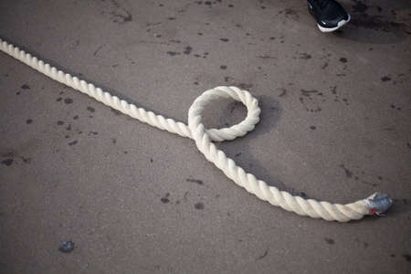 The end of the rope. The rope lies on the ground. Long rope on the pavement. Muscle training equipment. Ship mooring rope.の写真素材