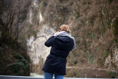 Girl photographer takes a picture. Girl holds a camera. The process of shooting on the street. Amateur photographer. Tourist captures the beauty.の写真素材