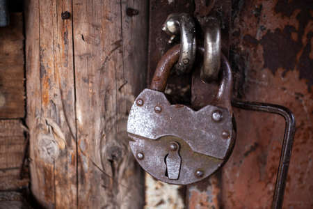 Big old lock on the door. A rusty lock closes the house. Background of antiquities. Reliable property protection. Metal products from steel.の写真素材