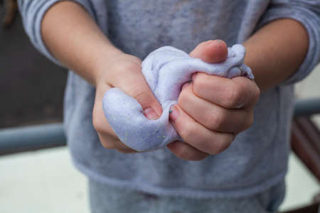 Slime in the hands of a child. A girl pulls an elastic band. Hobbies for preschoolers and schoolchildren. Fun for the little onesの写真素材