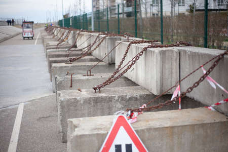 Concrete blocks with chains. Construction fencing. Lumps of stone stand in a row and interfere with the passage. Construction site.の写真素材