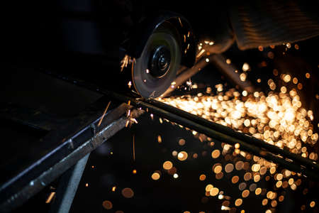 Metal processing. Sparks from the grinder. Grinding steel after welding. Cleaning the metal profile from the seams. Work in the workshop.の写真素材