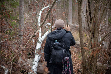 Tourist on a walk in the forest. The traveler entered an unknown territory. A man walks along the path. How not to get lost in the park. Alone with nature. Young naturalist. Walk along the forest belt.の写真素材
