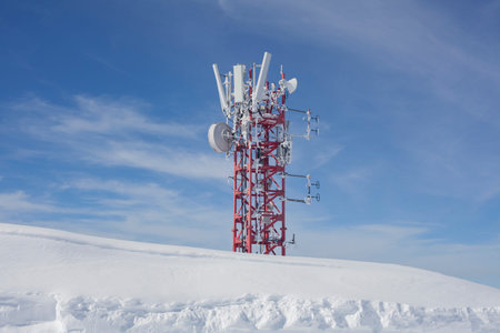 Communication antenna in the mountains. Broadcasting tower covered with snow. A radio transmitter...