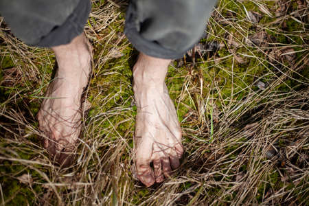 Bare feet in the grass. A guy stands barefoot on the ground. Foot massage in a natural environment. Bare feet. Rest in the summer in the nature.の写真素材