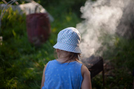Child in Panama. Girl in a cap with polka dots. Shooting a child from the back. Evening light when shooting. The girl walks in the fresh air. Child in a dark garden.の写真素材