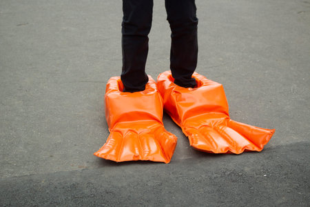 Big boots for a fun run. Doll shoes. Running with uncomfortable shoes. Funny orange rubber flippers.