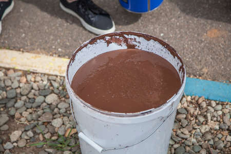 Paint bucket. Painting work in the summer. The painter prepared his tool. Oil paint in a jar. Work on the improvement of the park.の写真素材
