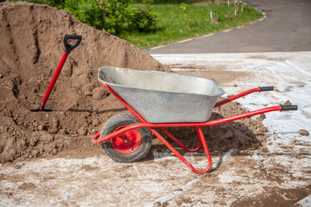 The gardener sprinkles a flower bed with a shovel. Creation of landscape design in the garden. The man is working. Gardening with a ground and a spade are tools of a gardener. A loose flower bed for flowers. Park decoration.の写真素材