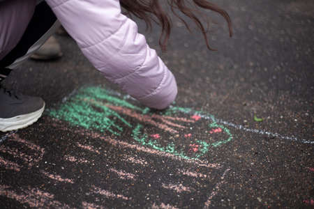 Drawing with chalk on the pavement. The child draws chalk on the road. children's creativity. The girl likes to draw.の写真素材