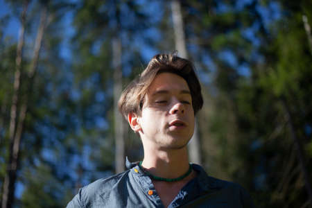 A guy in a shirt in a birch grove. A man stands in the woods. A person breathes air. The freshness of a summer day. Walk in the Park with a model.の写真素材