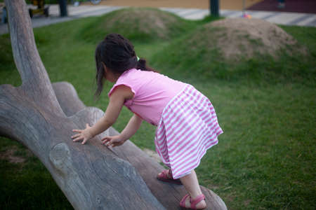 The girl is climbing a tree. A child on the Playground. Modern play area. Girl playing in the street.の写真素材