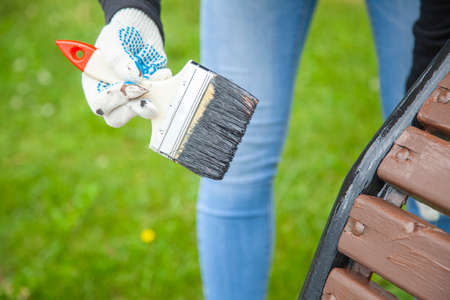 Brush with brown paint. Painting shops in a city park. Work on the improvement of urban facilities. Molar work. Brush close-up. Khudozhnik paints a tree. Oil paint in business.の写真素材