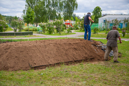 The gardener sprinkles a flower bed with a shovel. Creation of landscape design in the garden. The...