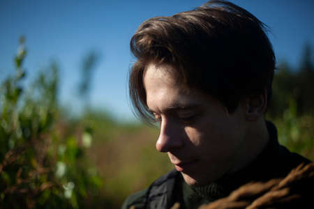 Portrait of a guy. Man's face on a background of blue sky. Walk in nature. Short-haired guy. Summer morning.の写真素材