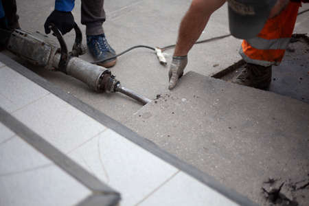 Removal of asphalt. Road surface repair. Working with a jackhammer. The road repair crew broke the asphalt.の写真素材