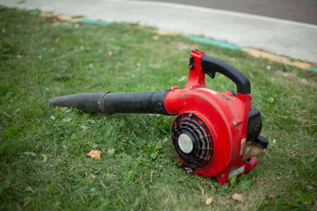 The garden vacuum cleaner lies on the grass. Blower for cleaning dry leaves.の写真素材