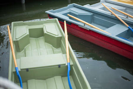 Boats at the pier. Pleasure boats for swimming on the lake. Lifeboats on the beach. Floating device made of plastic. Keeps well on water. The rowing oars are in place.の写真素材