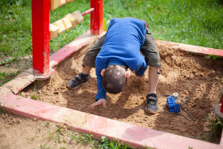 Child in the sandbox. Boy in the playground. The little guy plays with sand.の写真素材
