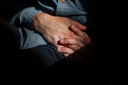 Hands folded together. The man clasped his hands together. The guy is holding his fingers. Significant closure gesture. The tense posture of the interlocutor. Filming with a hidden camera. Imitation of peeping. The man is sitting on a chair.の写真素材