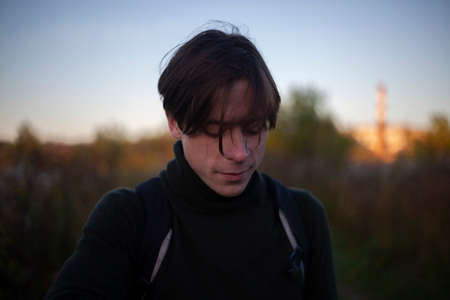 The guy is walking on the street. Young man at dawn. The man went out for a walk in nature. Handsome guy in casual clothes.の写真素材
