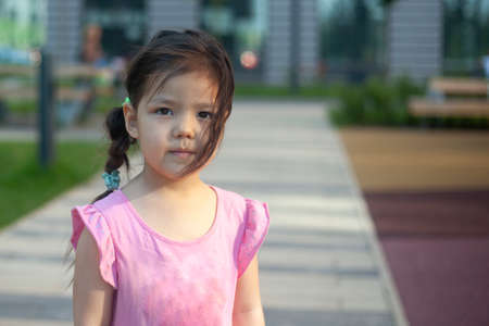 A girl of Asian appearance. Child in the playground. Cute little girl with black hair. Child on the street. Walk with my daughter.の写真素材