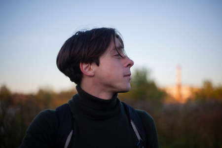 The guy is walking on the street. Young man at dawn. The man went out for a walk in nature. Handsome guy in casual clothes.の写真素材
