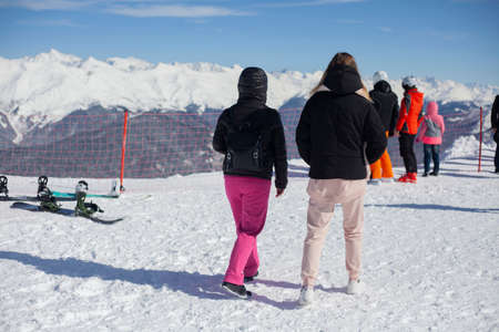 Girls are walking in a mountain ski resort. Rest in the mountains. Women wearing winter clothes. People on the observation deck at Rosa Khutor. Caucasian ridge. Tourist place. Girls travel.の写真素材
