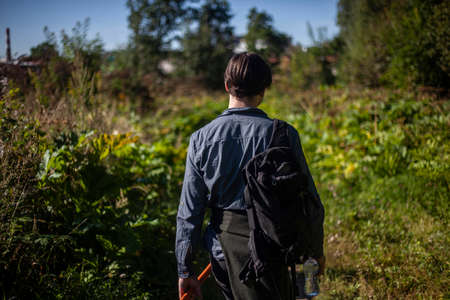 The guy travels to untouched places of nature. A man walks across the field. Young man shot from the back in the street. Walk on a summer day.の写真素材