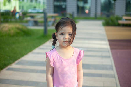 A girl of Asian appearance. Child in the playground. Cute little girl with black hair. Child on the street. Walk with my daughter.の写真素材