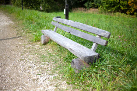 Wooden bench on the street. A place to rest. An unpainted park bench. Place for a walk. A shop on the path.の写真素材