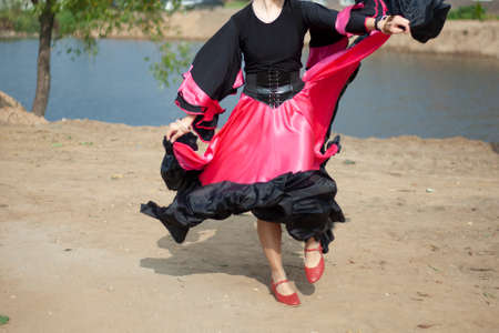 Dance in a gypsy dress. Speech on the street. Black and pink dress. Girl dancing. The beauty and grace of a gypsy woman.の写真素材