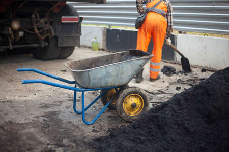Road repair. The worker carries the asphalt. Cargo trolley.の写真素材