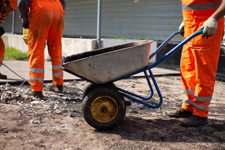 Road repair. The worker carries the asphalt. Cargo trolley.の写真素材
