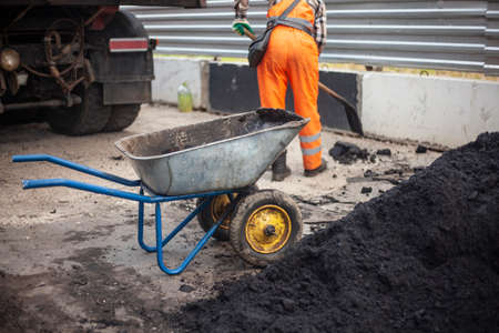 Road repair. The worker carries the asphalt. Cargo trolley.の写真素材