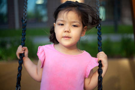 The girl is swinging on a swing. Play on the playground.の写真素材