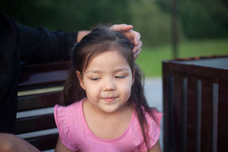 The child wants to sleep. The girl closed her eyes. Portrait of an Asian child. Child for a walk. Girl on the street.の写真素材