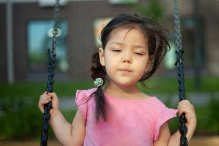 The girl is swinging on a swing. Play on the playground.の写真素材