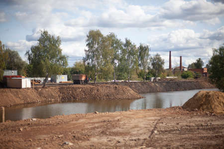 Construction work on the pond. Landscape creation. Correction of the shores of the lake. Sand embankment construction. Anchorage of the banks.の写真素材