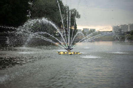 Fountain on the water. Fountain in the city park. Water jets. Summer city decoration. Walk along the pond.の写真素材