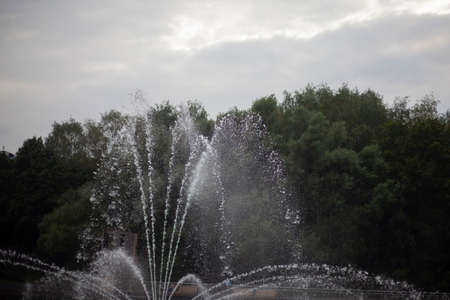 Fountain on the water. Fountain in the city park. Water jets. Summer city decoration. Walk along the pond.の写真素材