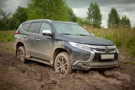 The wheels of the car are stuck in the mud. Off-road driving. SUV on a rural road. Waiting for evacuation. The black car cannot pass.の写真素材