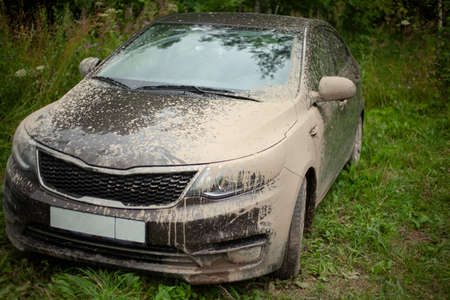 Car hood under a layer of mud. The car is covered in mud. Car after driving through puddles. A trip out of town. Dry dirt on the transport surface.の写真素材