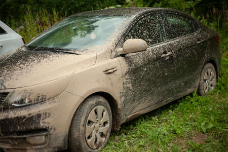 Car hood under a layer of mud. The car is covered in mud. Car after driving through puddles. A trip out of town. Dry dirt on the transport surface.の写真素材