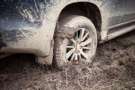 The wheels of the car are stuck in the mud. Off-road driving. SUV on a rural road. Waiting for evacuation. The black car cannot pass.の写真素材