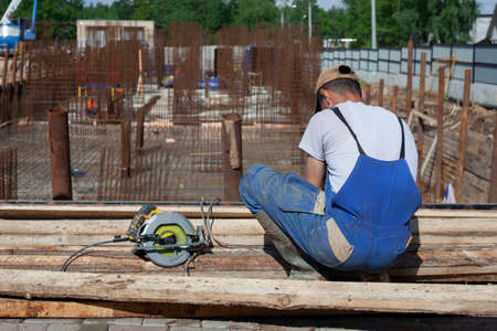 The worker is sawing the boards. The builder prepares the boards. Work at a construction site. A man cuts planks with an electric saw.の写真素材