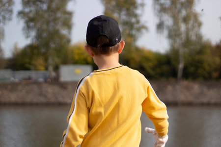 Boy in a yellow jacket. Shooting a child from the back in the sunlight. The boy walks in the street.